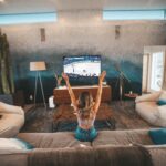 Blonde woman sitting on her couch cheering while watching a sports game on tv